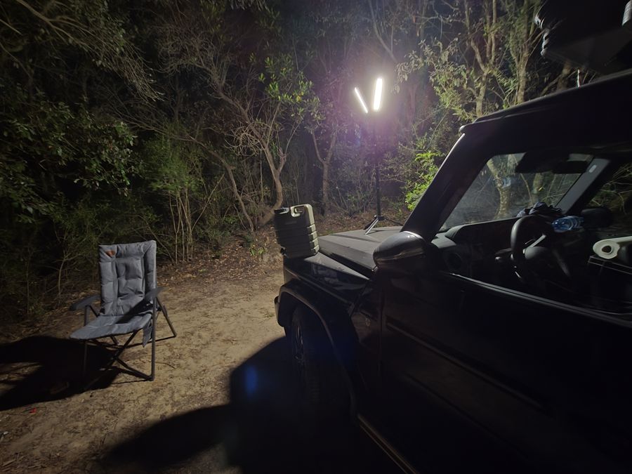Nachtlager mit Fahrzeug und Lampe im Wald